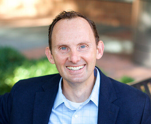 Dr. Christopher Blosser sitting on a bench outdoors.