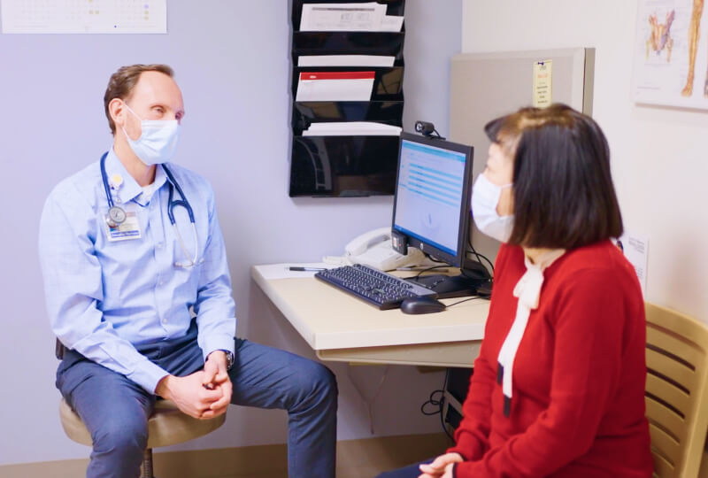 Dr. Blosser and a patient sitting and talking in an examination room.